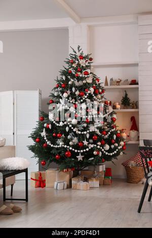 Wunderschön dekorierter Weihnachtsbaum und Geschenkschachteln im Zimmer. Innendesign Stockfoto