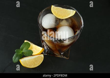 Köstlicher Cocktail mit Zitrone, Eisbällen und Minze auf schwarzem Tisch Stockfoto