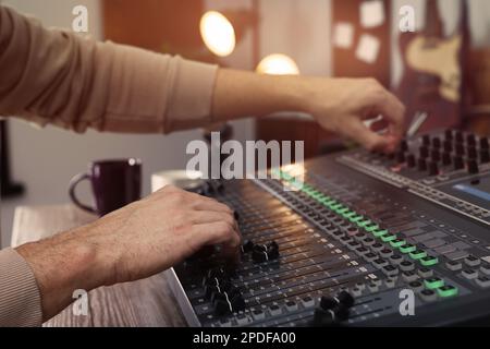 Mann, der mit einer professionellen Mischkonsole in einem modernen Radio-Studio arbeitet, Nahaufnahme Stockfoto