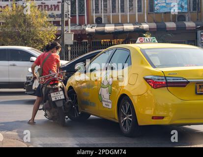 Eine Frau auf einem Motorrad löst einen Zusammenstoß mit einem Taxifahrer an einer Kreuzung Stockfoto