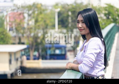 Eine junge Frau schaut von der Brücke über den Fluss Chao Phraya im Zentrum von Bangkok, Thailand Stockfoto