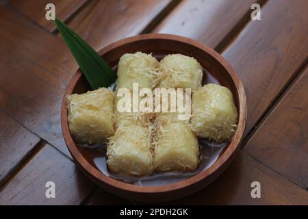 Nahaufnahme von lupis mit geriebener Kokosnuss und brauner Zuckersauce, serviert in einer Holzschüssel. Fotokonzept für traditionelle indonesische Speisen. Stockfoto