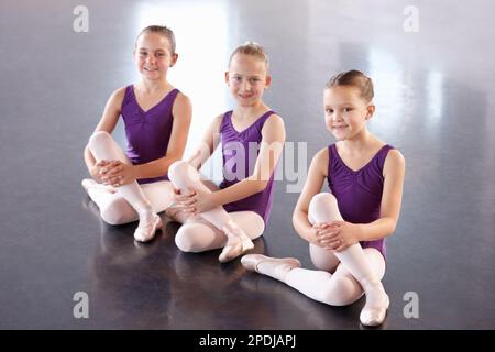 Ballerinas in der Herstellung. Fröhliche junge Ballerinas, die in einem Ballettstudio sitzen. Stockfoto