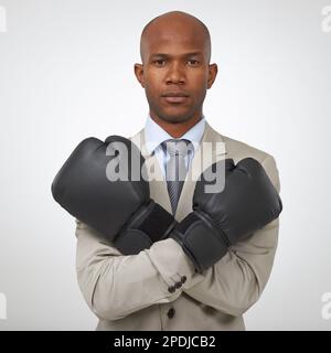 Bereit, alle geschäftlichen Mitbewerber zu übernehmen. Studioaufnahme eines afroamerikanischen Geschäftsmannes mit Boxhandschuhen. Stockfoto