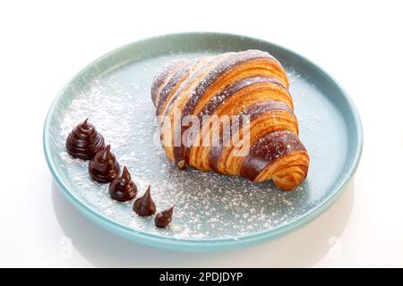 Brioche-Schokoladencroissant auf blauem Teller. Stockfoto