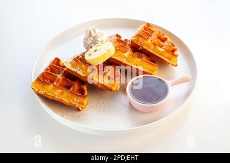 Waffelfrühstück mit Honigbutter Schlagsahne und Ahornsirup. Stockfoto