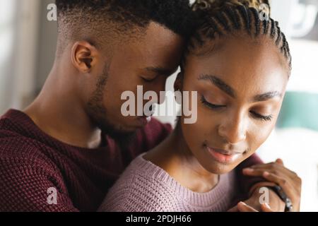 Glückliches afroamerikanisches Paar, das mit geschlossenen Augen umarmt Stockfoto