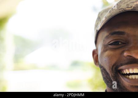 Porträt eines glücklichen afroamerikanischen Soldaten, der in die Kamera schaut und lächelt, mit Kopierraum Stockfoto