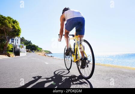 Genießen Sie die Landschaft beim Training. Beschnittene Ansicht eines Radfahrers, der entlang einer Meeresstraße radelt. Stockfoto