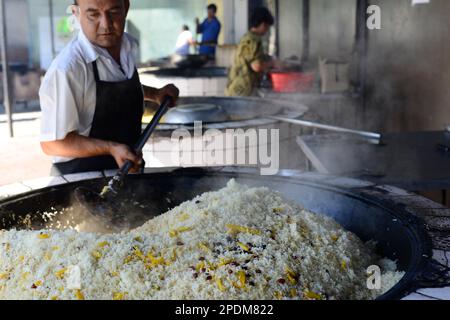 Riesige Kessel überlaufen mit Usbekistans beliebtestem Reisgericht im zentralasiatischen Plov Center in Taschkent, Usbekistan. Stockfoto