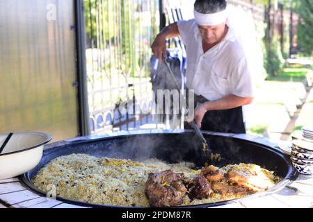 Riesige Kessel überlaufen mit Usbekistans beliebtestem Reisgericht im zentralasiatischen Plov Center in Taschkent, Usbekistan. Stockfoto