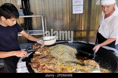 Riesige Kessel überlaufen mit Usbekistans beliebtestem Reisgericht im zentralasiatischen Plov Center in Taschkent, Usbekistan. Stockfoto