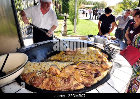 Riesige Kessel überlaufen mit Usbekistans beliebtestem Reisgericht im zentralasiatischen Plov Center in Taschkent, Usbekistan. Stockfoto