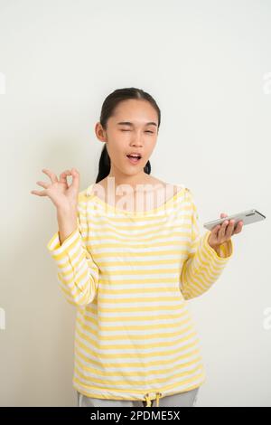 Der junge Aisan grillt auf isoliertem weißem Hintergrund und sendet eine Botschaft Stockfoto