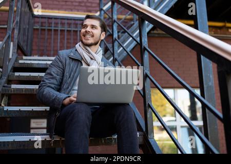 Erfolgreicher weißer Mann mit Laptop arbeitet im Außenbereich Stockfoto