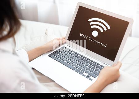 Menschen, die einen Laptop verwenden, verbinden sich mit dem Internet über das WLAN-Access-Point-Heimnetzwerksystem Stockfoto