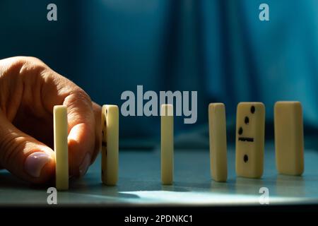 Weibliche Hand und Dominosteine auf blauem Hintergrund Stockfoto