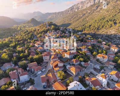 Von oben bilden farbenfrohe Häuser und lebendige Gärten im türkischen Ormana-Dorf einen markanten Kontrast zum zerklüfteten Taurusgebirge. Stockfoto