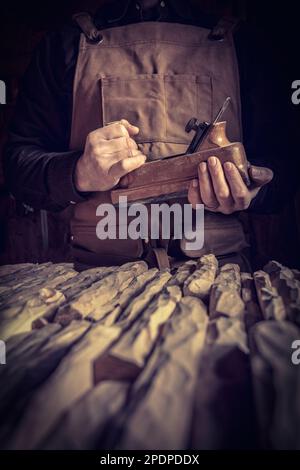 Zimmermann mit Lederschürze hält eine Hobelmaschine Stockfoto