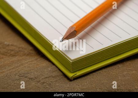 Ein liniertes Notizbuch mit einem Bleistift. Bereit, Notizen zu machen, Ideen zu skizzieren und Pläne zu schreiben. Stift und Papier bereit. Stockfoto