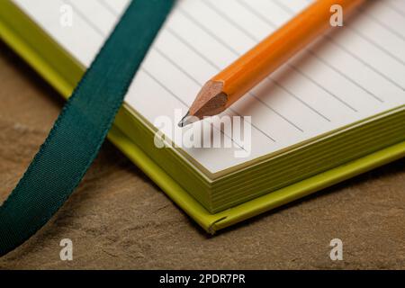 Ein liniertes Notizbuch mit einem Bleistift. Bereit, Notizen zu machen, Ideen zu skizzieren und Pläne zu schreiben. Stift und Papier bereit. Stockfoto