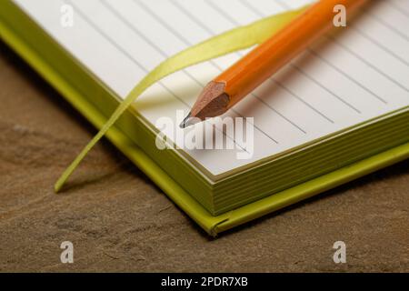 Ein liniertes Notizbuch mit einem Bleistift. Bereit, Notizen zu machen, Ideen zu skizzieren und Pläne zu schreiben. Stift und Papier bereit. Stockfoto