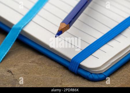 Ein liniertes Notizbuch mit einem blauen Bleistift. Bereit, Notizen zu machen, Ideen zu skizzieren und Pläne zu schreiben. Stift und Papier bereit. Stockfoto