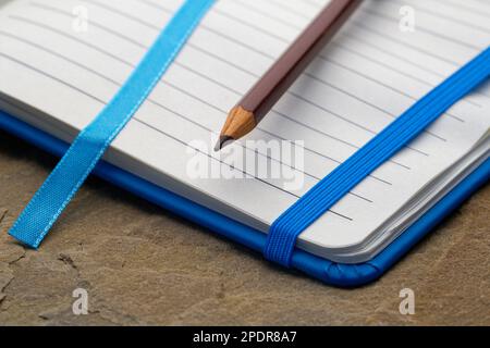 Ein liniertes Notizbuch mit einem braunen Bleistift. Bereit, Notizen zu machen, Ideen zu skizzieren und Pläne zu schreiben. Stift und Papier bereit. Stockfoto