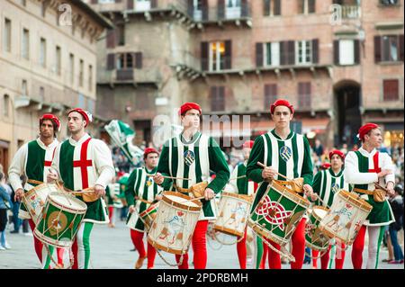 SIENA, ITALIEN - JULI 2013: Mitglieder der edlen Contrada dell'Oca tragen Fahnen mit einer gekrönten Gans auf dem Corteo Storico, einem historischen Kostümparadies Stockfoto
