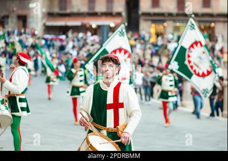 SIENA, ITALIEN - JULI 2013: Mitglieder der edlen Contrada dell'Oca tragen Fahnen mit einer gekrönten Gans auf dem Corteo Storico, einem historischen Kostümparadies Stockfoto