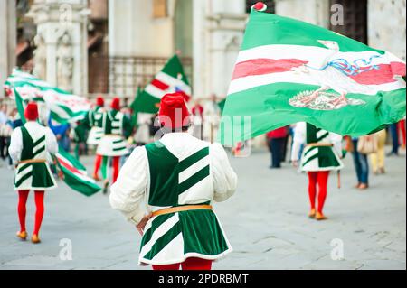 SIENA, ITALIEN - JULI 2013: Mitglieder der edlen Contrada dell'Oca tragen Fahnen mit einer gekrönten Gans auf dem Corteo Storico, einem historischen Kostümparadies Stockfoto