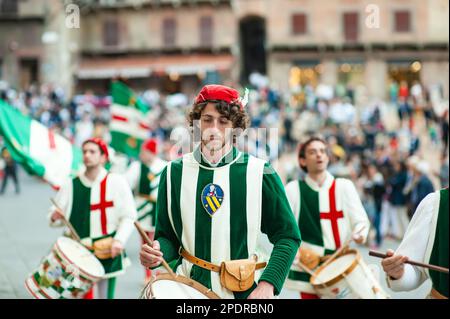 SIENA, ITALIEN - JULI 2013: Mitglieder der edlen Contrada dell'Oca tragen Fahnen mit einer gekrönten Gans auf dem Corteo Storico, einem historischen Kostümparadies Stockfoto