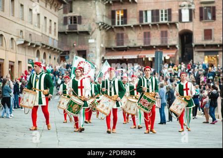 SIENA, ITALIEN - JULI 2013: Mitglieder der edlen Contrada dell'Oca tragen Fahnen mit einer gekrönten Gans auf dem Corteo Storico, einem historischen Kostümparadies Stockfoto