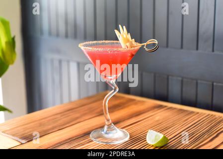 Alkohol-Cocktail Cosmopolitan auf Holztisch vor dunkler Wand mit Kopierbereich Stockfoto