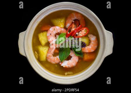 Eintopf mit Garnelen und Ananas isoliert auf schwarzem Hintergrund, Draufsicht Stockfoto