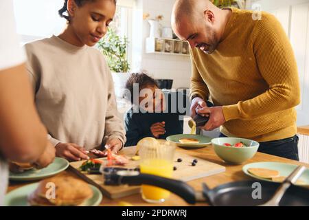Ein Junge mit Down-Syndrom isst Pfannkuchen zum Frühstück mit der Familie Stockfoto