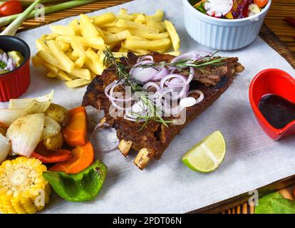 Gegrillte geräucherte Schweinerippchen mit pommes frites und Sojasoße und Salat auf Holzbrett Stockfoto