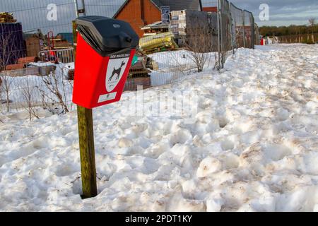 In Framlingham Suffolk hebt sich eine rote Mülltonne für Hundekacke von überraschend tiefem Schnee ab Stockfoto