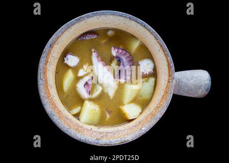 Gedünsteter Tintenfisch mit Kartoffeln in einem Topf, isolierter schwarzer Hintergrund, Seitenansicht Stockfoto