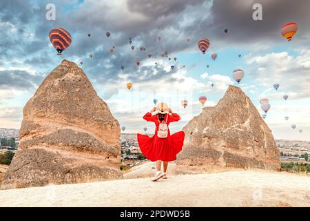 Sie steht in der warmen Sommerluft, Kleid flattert in der Brise, träumt von der weiten Welt, während sie die leuchtenden Ballons über Kappa gleiten sieht Stockfoto