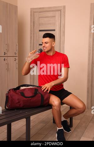 Schöner mann Trinkwasser in der Umkleide Stockfoto