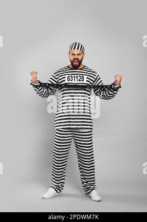 Emotionaler Gefangener in Spezialuniform mit angeketteten Händen auf grauem Hintergrund Stockfoto