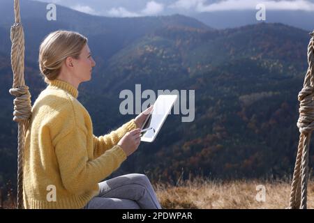 Junge Frau, die in Bergen mit einem Grafiktablett zeichnet Stockfoto