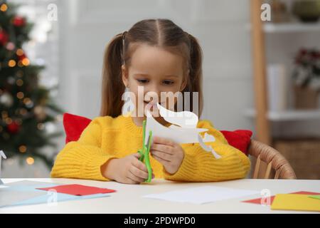 Süßes kleines Mädchen, das zu Hause einen Papierengel für den Nikolaustag macht Stockfoto