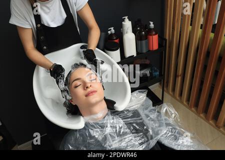 Friseur spült Färbemittel aus den Haaren der Frau im Schönheitssalon aus, über der Aussicht Stockfoto