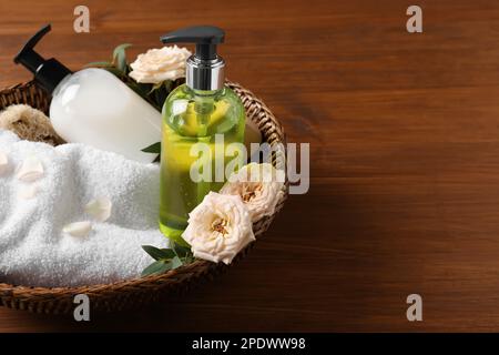 Spender für Flüssigseife, Handtuch und Rosen im Korb auf Holztisch Stockfoto