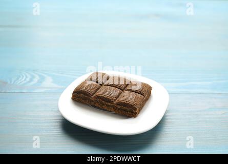 Weißer Teller mit köstlichem und gesundem Hämatogenriegel auf blauem Holztisch. Platz für Text Stockfoto