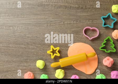 Spielteig in verschiedenen Farben mit Formen auf Holztisch, flach liegend. Platz für Text Stockfoto