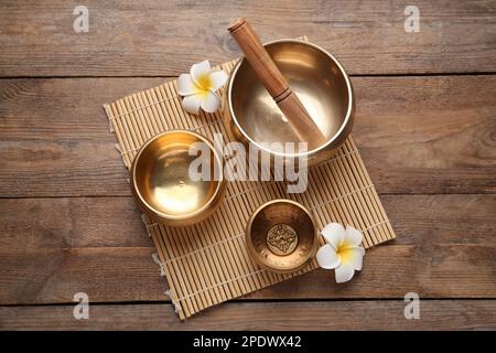 Goldene Gesangsschüsseln, Hammer und Blumen auf einem Holztisch, Blick von oben Stockfoto
