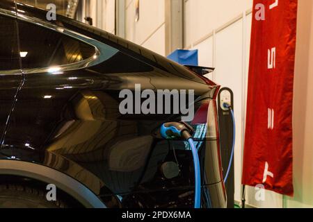 ESSEN, DEUTSCHLAND - 01. Dezember 2017: Ein Elektrofahrzeug des US-amerikanischen Herstellers Tesla wird auf der Essener Motormesse im Dezember an eine Ladestation angeschlossen Stockfoto